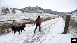Una mujer camina su perro sobre la reciente nevada en el parque Chautauqua, en Boulder, Colorado, el miércoles, 11 de noviembre de 2015.
