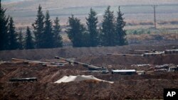 Turkish soldiers are seen on artillery pieces holding their positions near the border with Syria in Sanliurfa province, Turkey, Tuesday, Oct. 8, 2019. 