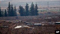 Turkish soldiers are seen on artillery pieces holding their positions near the border with Syria in Sanliurfa province, Turkey, Oct. 8, 2019. 