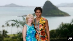 FILE - U.S. first lady Michelle Obama poses with Laureen Harper, spouse of then-Canadian Prime Minister Stephen Harper, at Kualoa Ranch on the east side of Oahu in Kaaawa, Hawaii, Nov. 13, 2011. The island of Mokolii, also know as the Chinaman's Hat island, in the background.