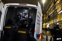 FILE - Detained men are seen in a police vehicle during a protest against a court ruling ordering Russian opposition leader Alexey Navalny jailed for nearly three years, in downtown Saint Petersburg, Feb. 2, 2021.