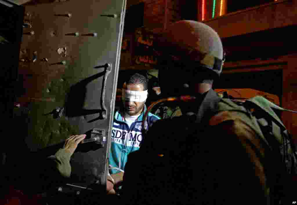 Israeli soldiers detain a blindfolded Palestinian man in the West Bank city of Hebron, July 2, 2014. 