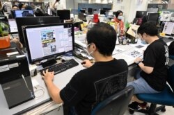 FILE - Journalists works in the newsroom of the Apple Daily newspaper in Hong Kong, May 11, 2021.