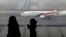 FILE - A woman and a girl look at a Malaysia Airlines plane on the tarmac of Kuala Lumpur International Airport.