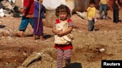 FILE - A girl carries bread outside the tents in the Bab Al-Salam refugee camp in Azaz, Oct. 27, 2014.