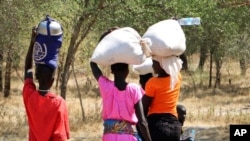 FILE - Women and girls walk back after getting food in Bentiu, a 38-kilometer journey, using a path through the bush for fear of being attacked on the main road, near Nhialdu in South Sudan. Rape has been used widely as a weapon in South Sudan.