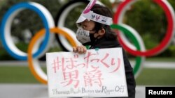 Pengunjuk rasa anti-Olimpiade di depan monumen cincin Olimpiade di luar markas besar Komite Olimpiade Jepang selama unjuk rasa, di tengah wabah COVID-19, di Tokyo, Jepang 18 Mei 2021. (Foto: REUTERS/Issei Kato)