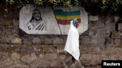 FILE - A traditionally-dressed Ethiopian woman walks past a mural depicting Ethiopia's Emperor Tewodros II in Addis Ababa, Ethiopia, June 1, 2007