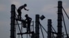 FILE - Workers on scaffolding are silhouetted at a construction site near Phnom Penh, Cambodia.