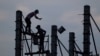 FILE - Workers on scaffolding are silhouetted at a construction site near Phnom Penh, Cambodia, March 21, 2017. Despite a growing economy, Cambodian construction workers earn as little as $2.50 a day.