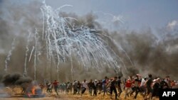 Les Palestiniens cherchent à se protéger des gaz lacrymogènes lors d'affrontements avec les forces de sécurité israéliennes près de la frontière entre Israël et la bande de Gaza, à l'est de Jabalia, le 14 mai 2018. ( Archives)