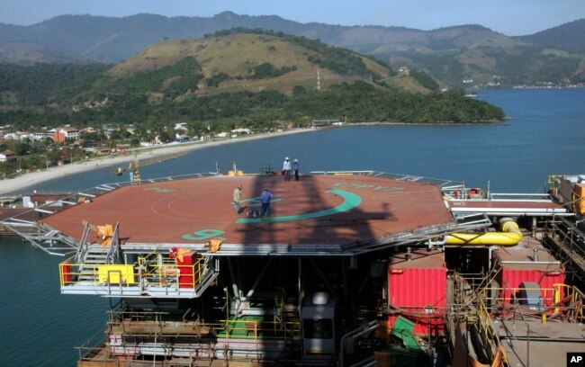 FILE - Petrobras workers walk on platform 51 "Majuro" in Angra dos Reis, Brazil, Aug. 21, 2008. (AP Photo/Ricardo Moraes, File)