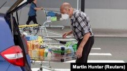 New Zealand, Christchurch, Brian Green, 76, wears a mask as he takes out products from his supermarket