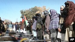 A former Taliban militant, center, holds the national flag of Afghanistan as others stand while they are seen during a joining ceremony with the Afghan government in Ghazni, west of Kabul, Afghanistan, January 16, 2012.