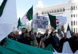 An Algerian woman holds a banner reading "No to foreign interference" during a march against EU interference into Algeria's policy, Nov. 30, 2019 in Algiers after the European Parliament on Thursday condemned the reality of human rights in Algeria.