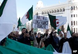 An Algerian woman holds a banner reading "No to foreign interference" during a march against EU interference into Algeria's policy, Nov. 30, 2019 in Algiers after the European Parliament on Thursday condemned the reality of human rights in Algeria.