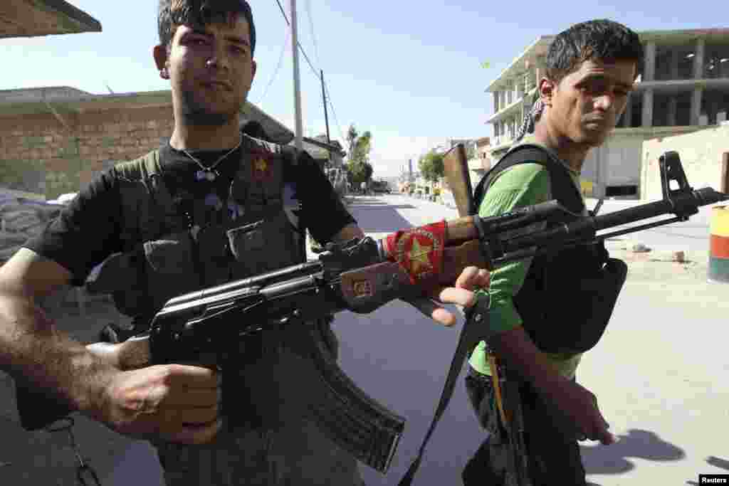 A Kurdish fighter from the Popular Protection Units (YPG) shows his weapon decorated with his party's flag, as a fellow fighter looks on in Aleppo's Sheikh Maqsoud neighbourhood, June 7, 2013. Kurdish fighters from the YPG joined the Free Syrian Army to f