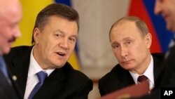Russian President Vladimir Putin, right, and his Ukrainian counterpart Viktor Yanukovych, left, react after signing an agreement in Moscow, Dec. 17, 2013.