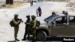 Israeli soldiers stand guard at the entrance of Yatta near the West Bank city of Hebron, June 9, 2016. 