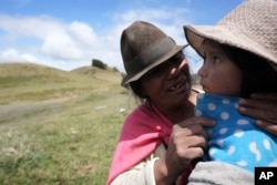 A Native woman soothes her daughter before giving her a flu shot in Cotopaxi, Ecuador on December 2, 2022. (AP Photo/Dolores Ochoa)