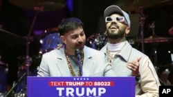 Anuel AA (derecha) y Justin Quiles hablan antes de que el presidente electo Donald Trump llegue a un mitin previo a la 60ª Investidura Presidencial, el domingo 19 de enero de 2025, en Washington. (Foto: AP)