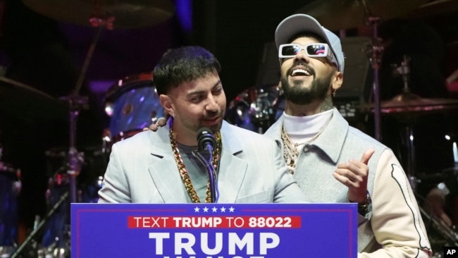 Anuel AA (derecha) y Justin Quiles hablan antes de que el presidente electo Donald Trump llegue a un mitin previo a la 60ª Investidura Presidencial, el domingo 19 de enero de 2025, en Washington. (Foto: AP)