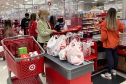 FILE - A customer wearing a face mask waits to get a receipt from a cashier at a Target store in Vernon Hills, Illinois, May 23, 2021. Low interest rates in the U.S. have been fueling fears of unchecked inflation.