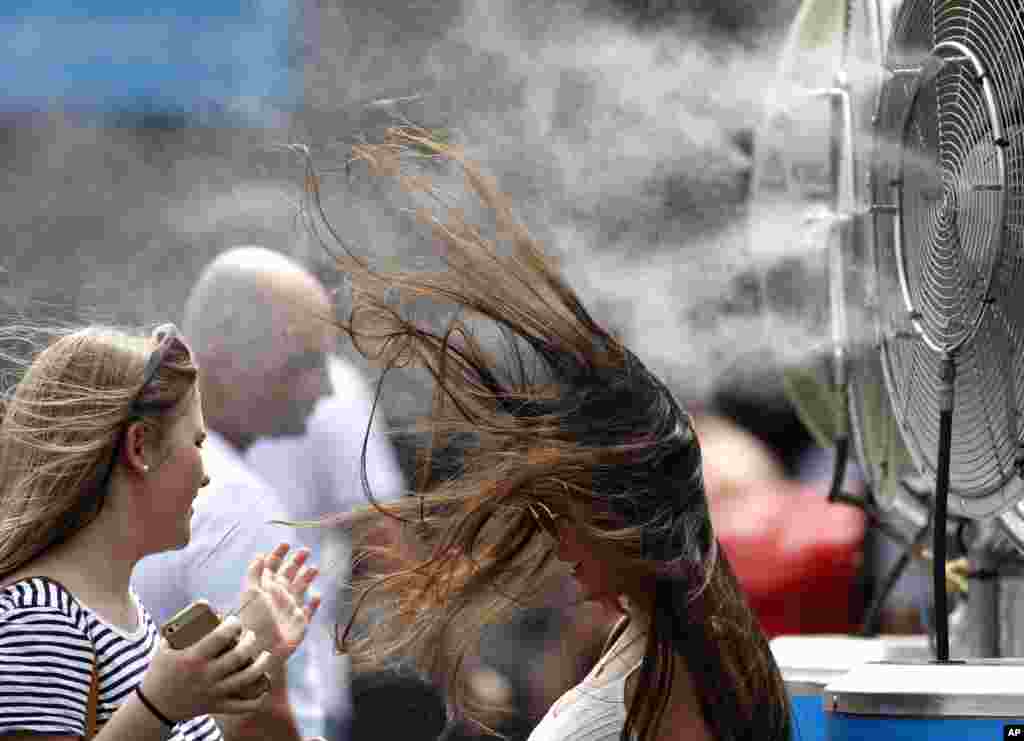 A spectator cools herself at a water- spraying fan at the Australian Open tennis championships in Melbourne, Australia.