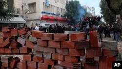 Tunisian demonstrators stand behind a barricade as they clash with Tunisian security forces during an anti-government protest in Tunis on February 26, 2011.