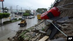 A car lies on its side after a portion of a hill collapsed due to heavy rains in the Pacific resort city of Acapulco, Mexico, Sept. 15, 2013.