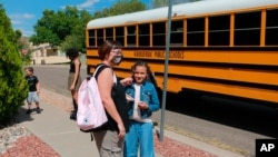 Dawn Lourenco plays with her daughter Mimi's hair after the 8-year-old got home from school on Friday, Sept. 3, 2021, in Albuquerque, N.M. Lourenco's two other children were forced to learn remotely due to outbreaks in their schools. Her daughter…