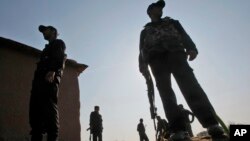 FILE - Pakistani policemen stand at the site of an attack, on the outskirts of Peshawar, Pakistan, Feb. 12, 2014.