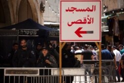 Israeli police stand at a checkpoint with a sign in Arabic that reads "Al-Aqsa Mosque," in the Old City of Jerusalem, for Friday prayers during Ramadan, April 23, 2021.