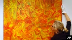 FILE - Christie's employee Rhiannon Broomfield poses for photographs beside the untitled painting by Aboriginal artist Emily Kame Kngwarreye which features in the forthcoming Modern and Contemporary Australian Art auction at the auction house's offices in London, Friday, Dec. 7, 2007. 