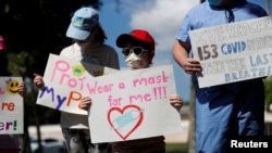 Los partidarios del uso de máscaras en las escuelas Sofia Deyo, 11 años, y su hermano Matthew Deyo, 6, protestan frente al edificio de administración de las escuelas del condado de Pinellas en Largo, Florida, EE. UU., el 9 de agosto de 2021.