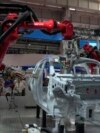 FILE - Visitors look on as robotic arms assemble a vehicle frame in Beijing on Aug. 17, 2023. Factory activity in China grew for the first time in six months in September.