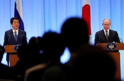 FILE - Russian President Vladimir Putin, right, and Japanese Prime Minister Shinzo Abe attend a news conference at the G-20 leaders summit in Osaka, Japan, June 29, 2019.