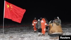 Researchers work around Chang'e-5 lunar return capsule carrying moon samples next to a Chinese national flag, after it landed in northern China's Inner Mongolia Autonomous Region, December 17, 2020. 