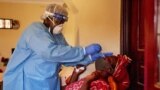 FILE - A member of South Sudanese Ministry of Health Rapid Response Team takes a nasal sample from a woman at her home after she came into into contact with a confirmed COVID-19 case, in Juba, South Sudan, April 14, 2020.