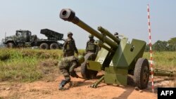 Des soldats des forces armées de la République démocratique du Congo (FARDC) installent une pièce d'artillerie mobile à côté d'un lance-roquettes multiples mobile à Matombo, Beni, Nord Kivu, le 13 janvier 2018.