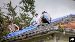 Residentes reparan un tejado después del paso de la tormenta tropical Debby por Isle of Palms, Carolina del Sur, el 6 de agosto de 2024.