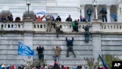 Supporters of President Donald Trump climb the west wall of the the U.S. Capitol on Wednesday, Jan. 6, 2021, in Washington. (AP Photo/Jose Luis Magana)