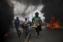 Protestors run past burning tires during a march demanding the resignation of Haiti's President Jovenel Moise, at the 217th anniversary of the Battle of Vertieres, the last major battle of Haitian independence from France, in Port-au-Prince, Haiti.