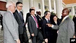 Uganda President Museveni (R) talks to UK Mission to the UN Ambassador Mark Lyall Grant (L) as members of the UN Security Council look on at State House Entebbe, Uganda, 06 Oct. 2010