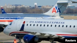A US Airways Express plane departs from a gate past an American Airlines plane at the Ronald Reagan Washington National Airport in Arlington County, Virginia, February 10, 2013.