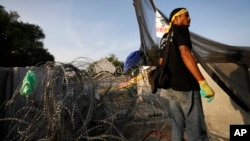 An anti-government protester stands in front of barbed wire set up by police near the compound of Thai Prime Minister Yingluck Shinawatra's office in Bangkok, Dec. 2, 2013. 