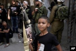 A Palestinian child poses with a rifle during the funeral of Qasim Qasim, 23, in the West Bank city of Tulkarem on Oct. 14, 2023. Qasim was killed in clashes with Israeli forces on Friday following a demonstration supporting the Gaza Strip.