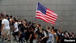 Protesters hold up their hands to symbolize five demands and a U.S. flag during a rally to the U.S. Consulate General in Hong Kong, Sept. 8, 2019.