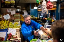 József Varga, owner of a grocery in Budapest's Grand Market Hall, sells vegetables on April 8, 2023. (AP Photo/Denes Erdos)