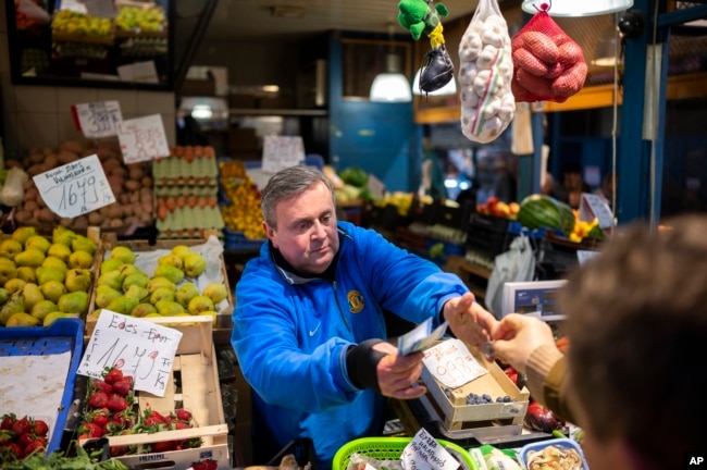 József Varga, owner of a grocery in Budapest's Grand Market Hall, sells vegetables on April 8, 2023. (AP Photo/Denes Erdos)